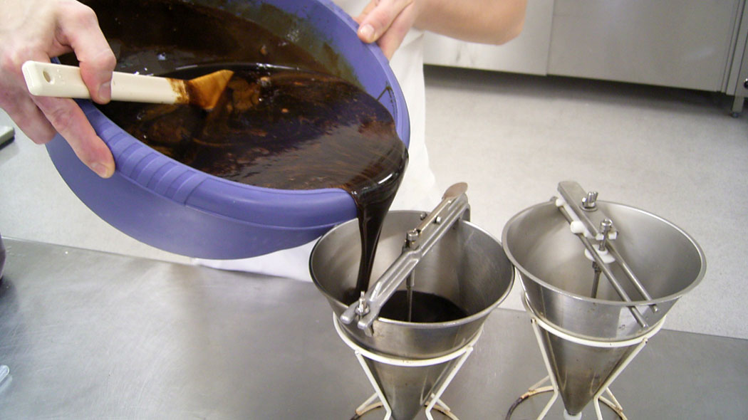 Pouring the licorice syrup into the disposal tins before portioning it into the starch model.